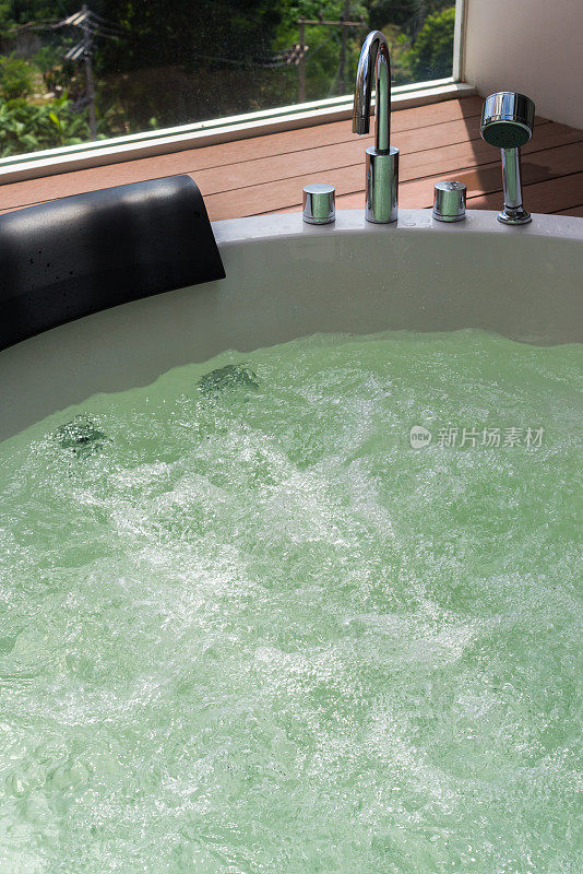 白色漩涡浴缸和气泡与钢水龙头和莲蓬头