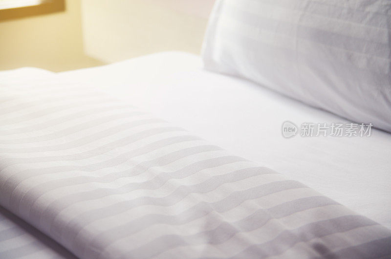 卧室里白色的床上放着白色的枕头