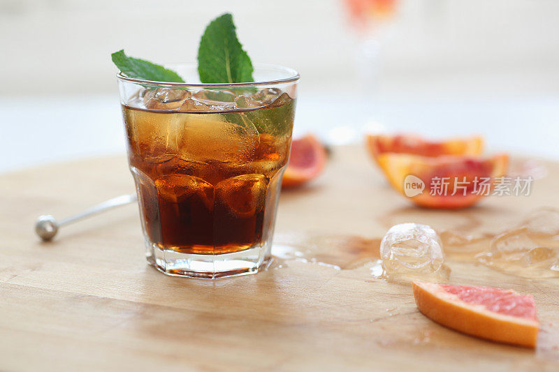 鸡尾酒威士忌可乐加冰在玻璃杯中。木板上放着水果的碎片。照片景深。