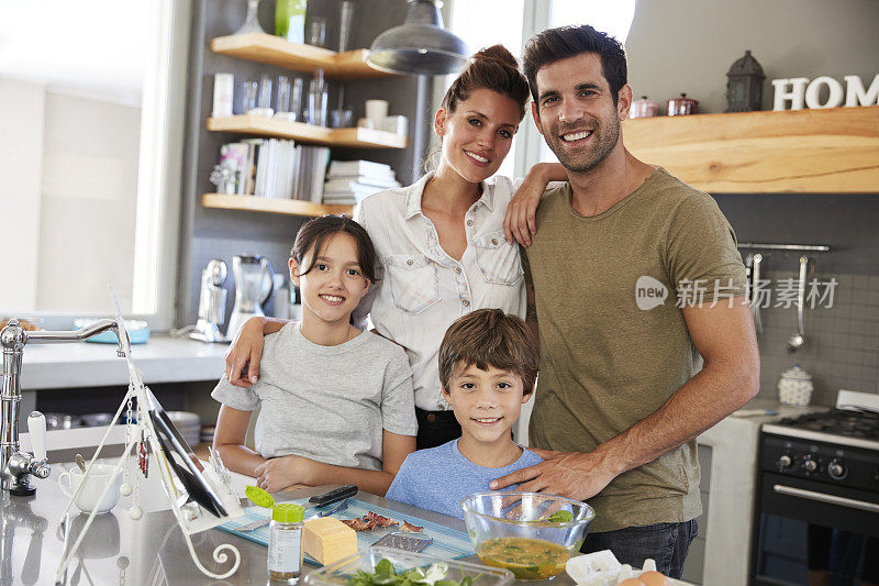 家庭在厨房的肖像照食谱在数字平板电脑上