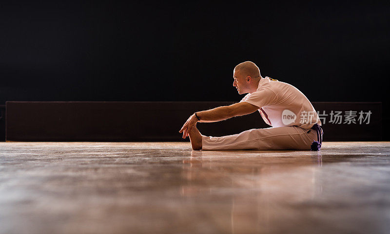 卡泼卫拉运动员在拼花地板上伸展双腿的侧视图。