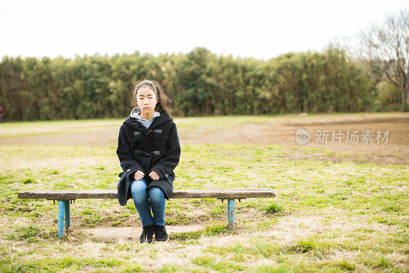 一个女孩正坐在公园的长凳上