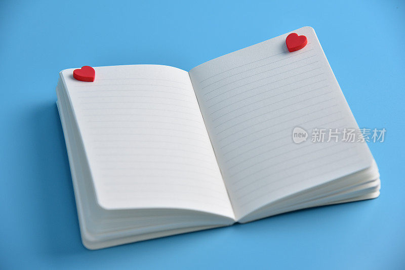 两颗红心和打开的笔记本空白页。