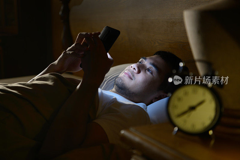 年轻人晚上在床上玩智能手机