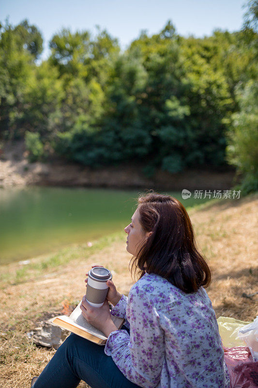 一个年轻女子坐在夕阳下的湖上看书。