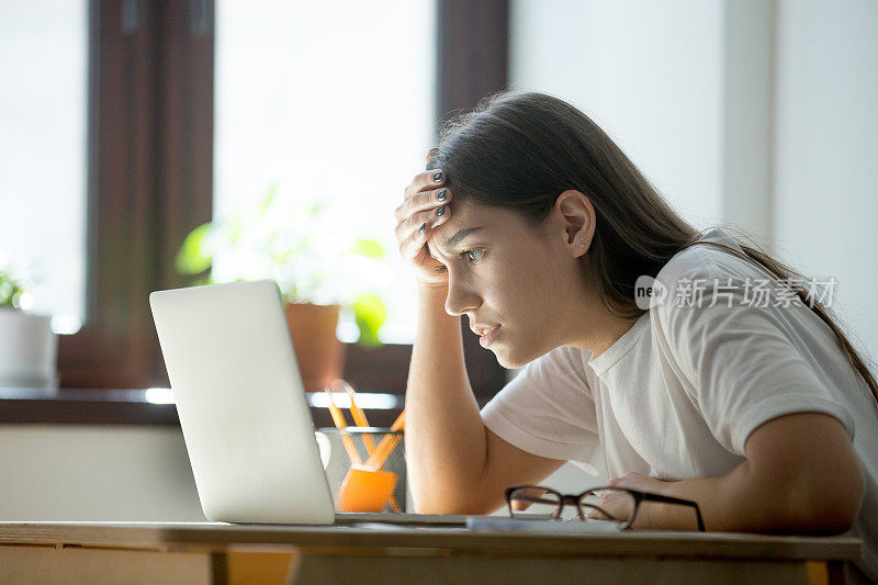 疲惫沮丧的女人在笔记本电脑上专心阅读一份合同