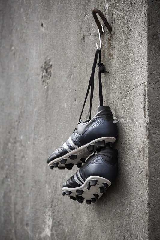 足球鞋挂在粗糙的混凝土墙上。