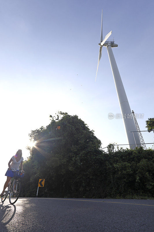 女人骑着自行车经过风力涡轮机