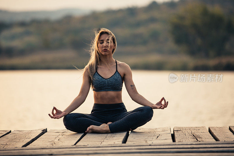 健康和运动的年轻女子在湖边做瑜伽