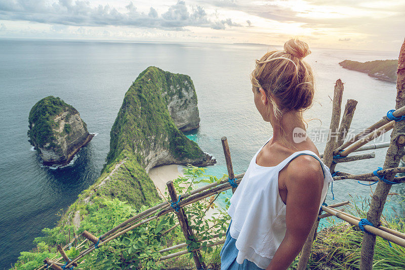 年轻女子俯瞰克林金海滩——蓝色和绿色的沙子，美丽的山在海上形成。旅游目的地度假，人们好奇的概念自然风景