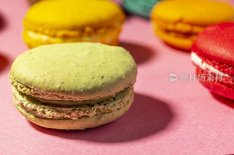 近距离拍摄色彩鲜艳的自制蛋白杏仁饼干，背景是粉红色。