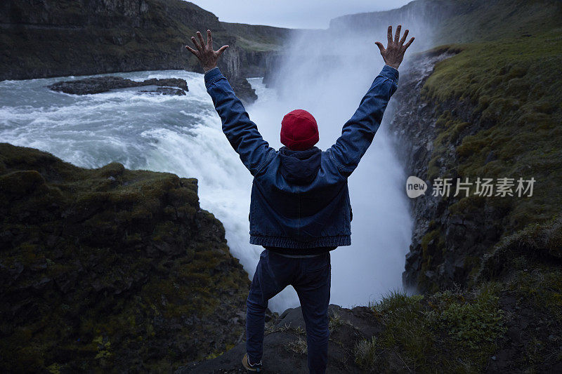 自然美。旅行欣赏瀑布。张开双臂