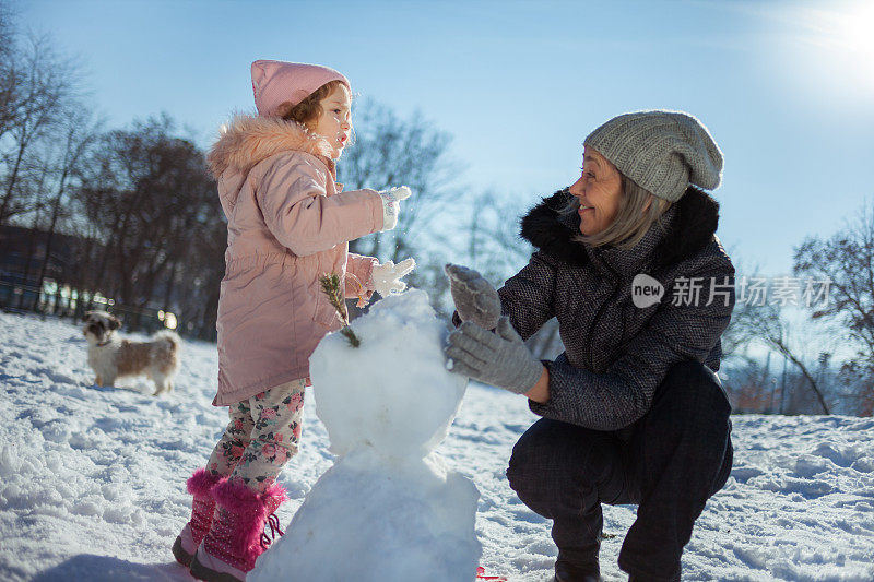 奶奶和孙女在冬天堆雪人