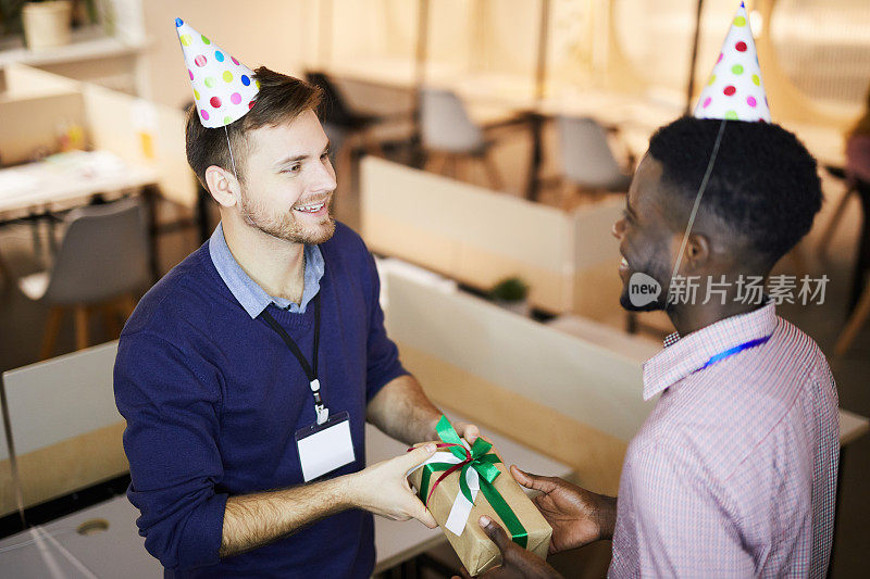 开朗英俊的男人给同事礼物，同时庆祝他的生日