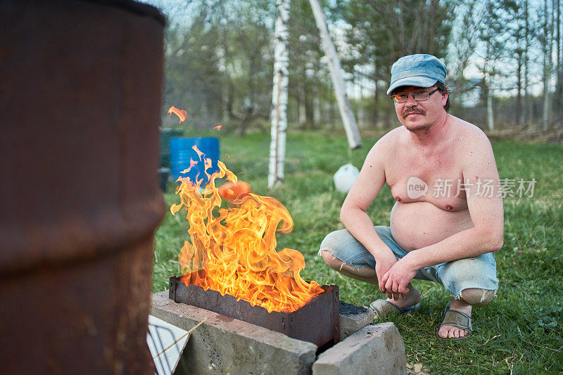 中年男子点燃野餐烤架上的火