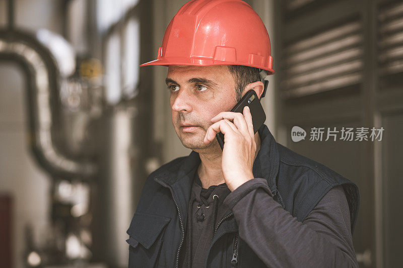 在工厂里使用手机的男性技术员