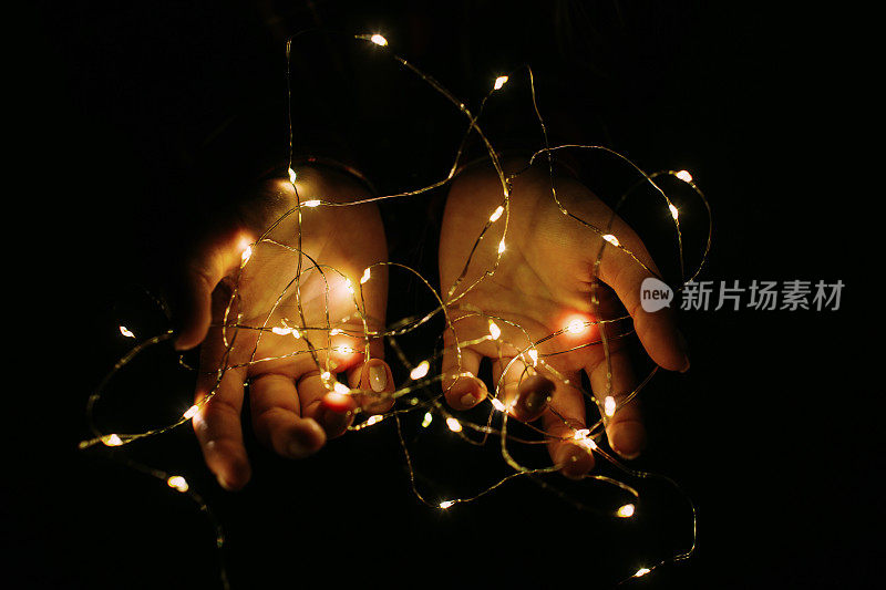 圣诞彩灯在女性的手中温暖地闪烁着。