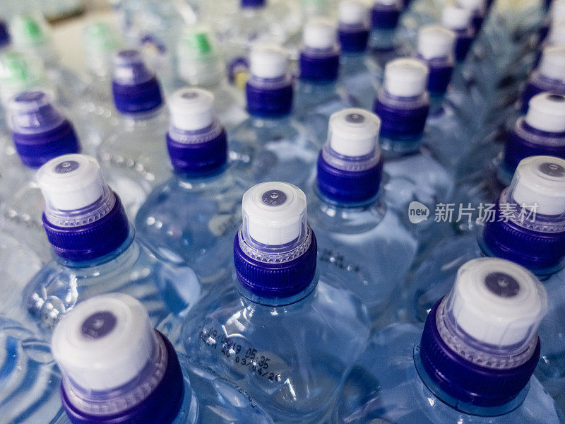 装水的塑料瓶。一排排带螺旋盖的装满水的塑料瓶。
