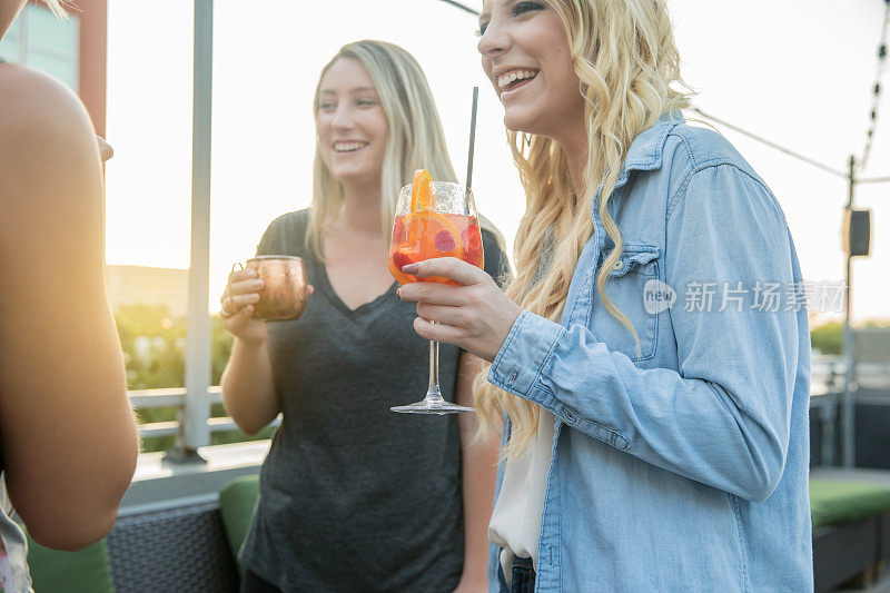 女士们晚上在城市的屋顶酒吧日落