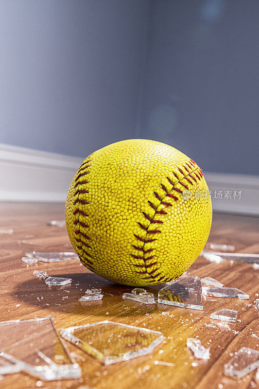 地板上有一个黄色的垒球和碎玻璃