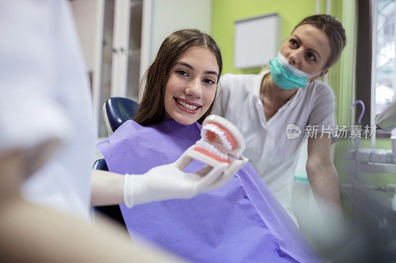 牙医向十几岁的病人展示牙齿模型