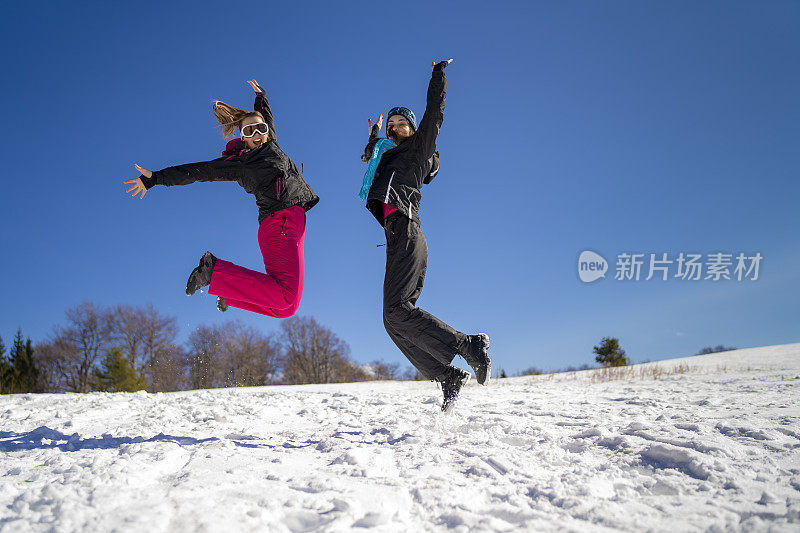 年轻的滑雪者在雪山上嬉戏跳跃