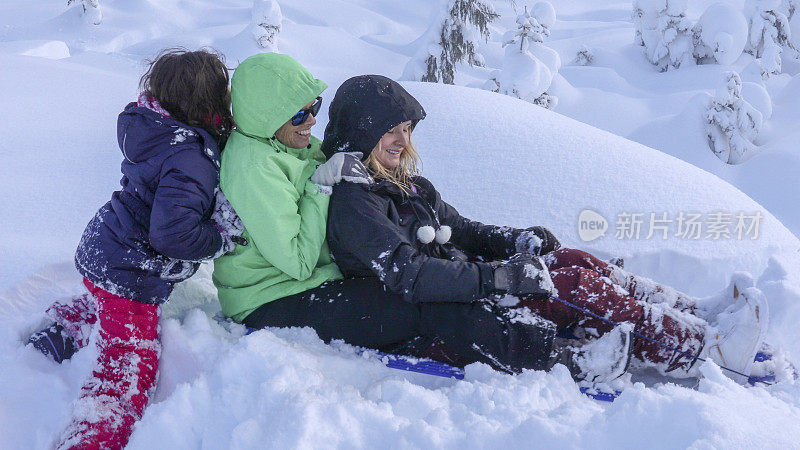 母女俩滑着雪橇滑下山坡