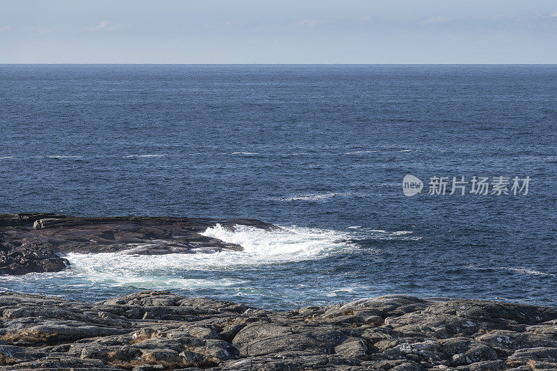 在早春的一个多风的日子里，岩石嶙峋的海岸线和海面上的白色浪花