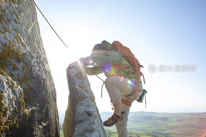 登山者在日出时攀登岩面