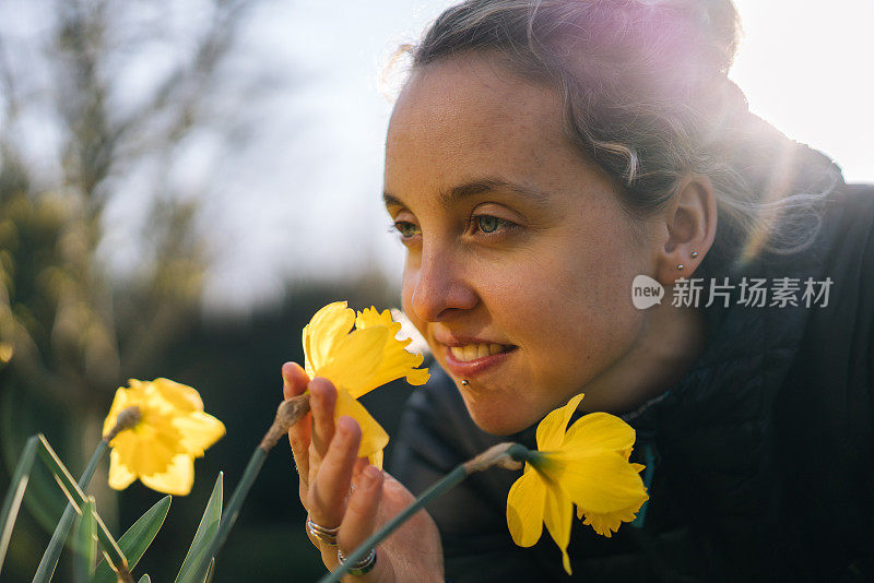 年轻女子俯身闻花香