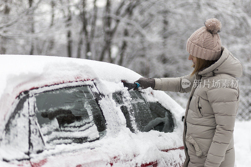 年轻女子用刮冰器刮雪