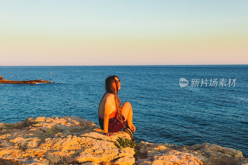 在法国南部的海岸上，一位年轻的女子与灿烂的夏日落日相遇