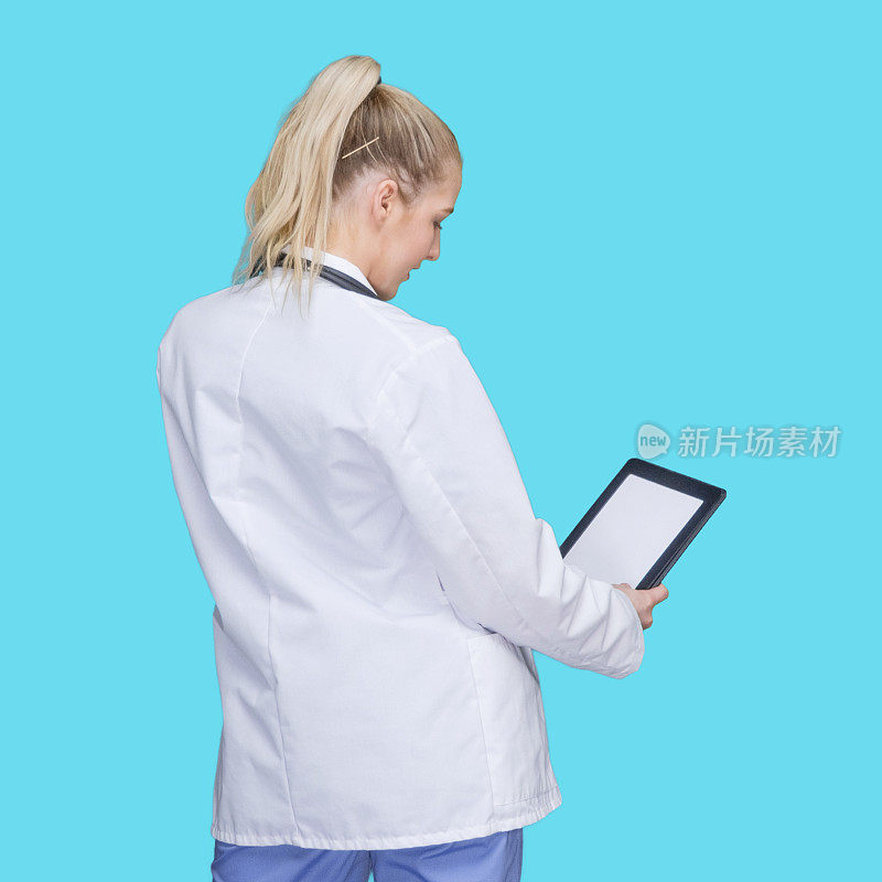 白人女医生站在蓝色背景下，穿着实验服，使用触摸屏