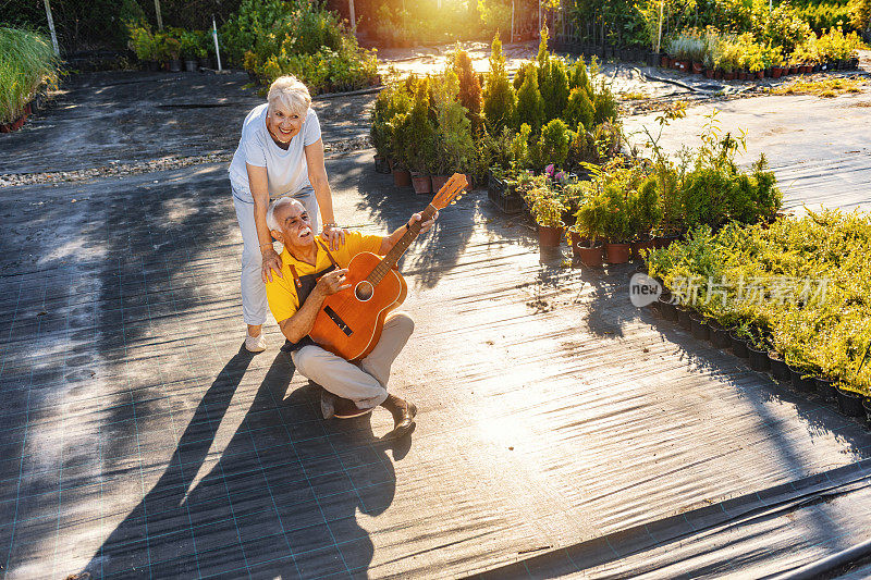 快乐的老人给他的妻子弹吉他