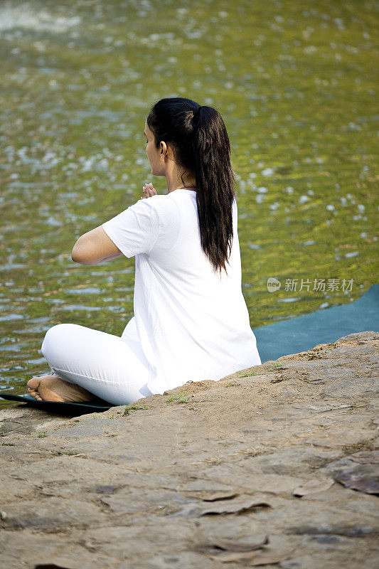 在湖边做瑜伽姿势的女人