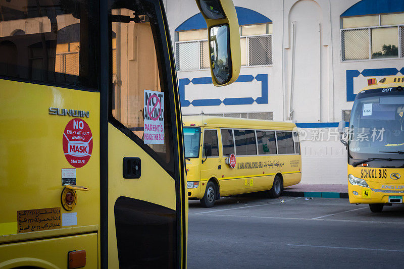 黄色校车在阿布扎比，阿拉伯联合酋长国，迪拜，阿联酋，海湾，中东。在校车上，意识标志和符号是用阿拉伯语写的。