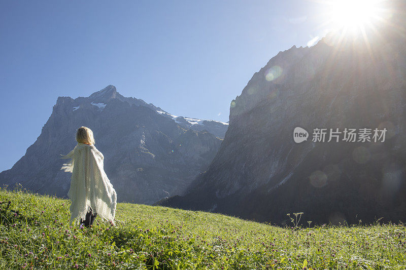 日出时，裹着毯子的女人在草地上放松