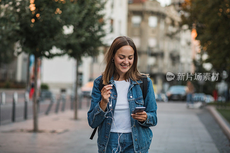 一个年轻女人走在城市里，看着手机