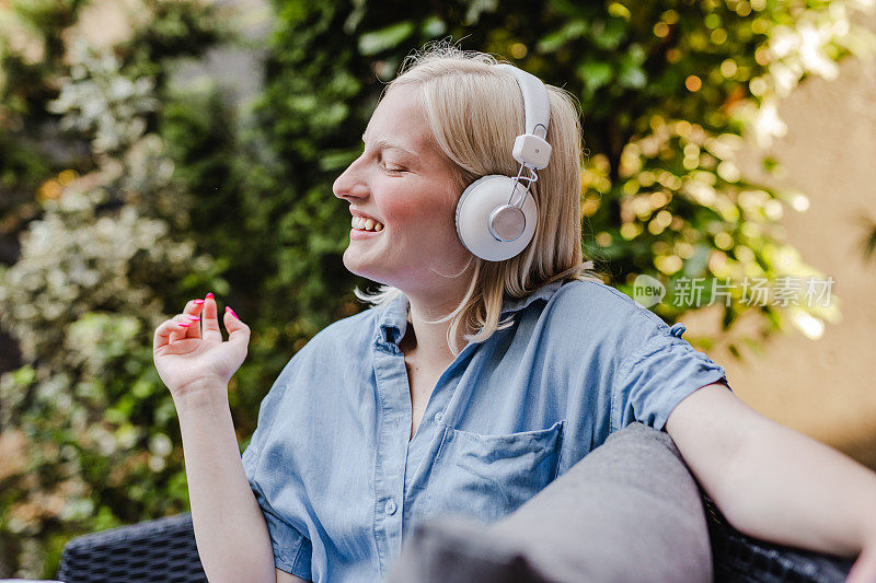 一个年轻女子戴着耳机在阳台上听着轻松的音乐