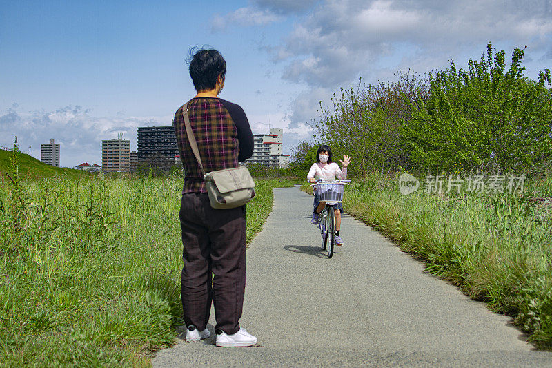 女孩骑着自行车向她妈妈走来