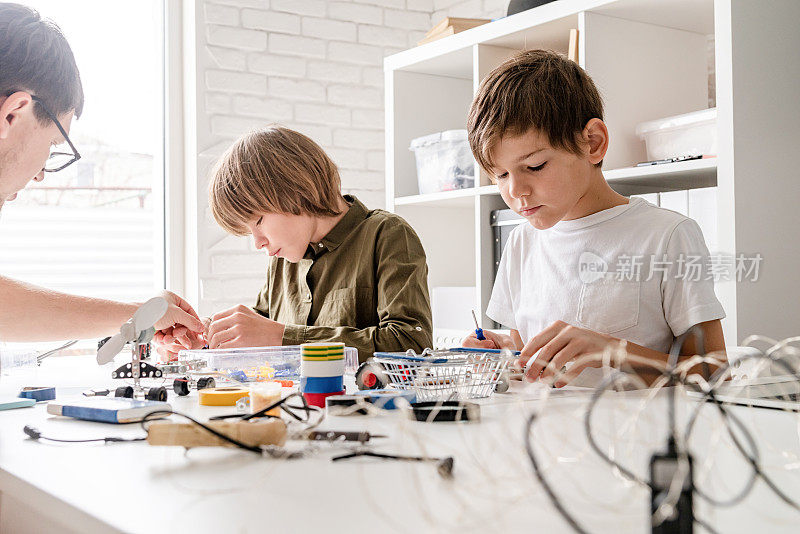 小男孩和老师在车间里建造机器人车