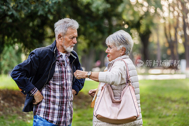 一位老人和他的妻子在一个公园里进行严肃的讨论。