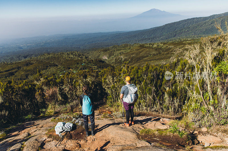 在乞力马扎罗山国家公园，男女徒步旅行者在山顶欣赏梅鲁山的美景