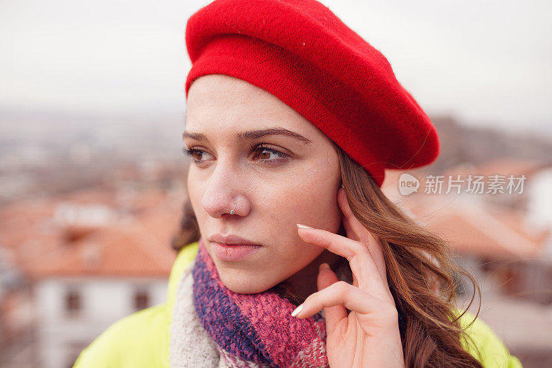 一个戴着红色贝雷帽的女人的肖像。一个城市里的女人