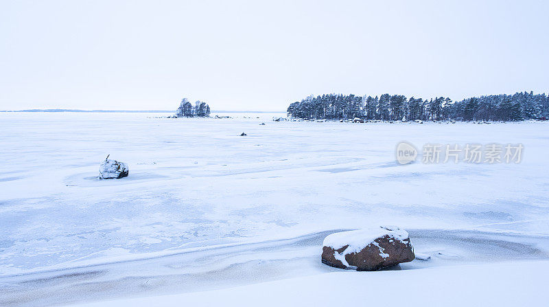 冬天的风景。雪覆盖了海湾上的冰和地平线上的一座岛屿。