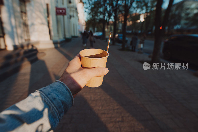 早晨的城市里，POV男人拿着一杯带着外卖茶和柠檬的杯子