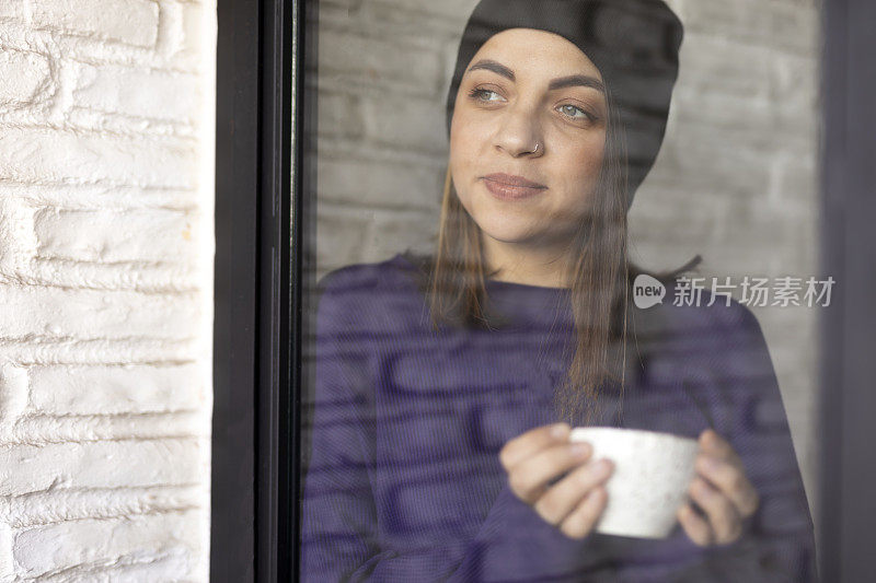 侧面的美丽女人喝咖啡的窗口