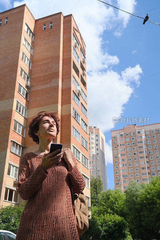 成熟的女人正在寻找城市里的地址。她正在用智能手机上的地图