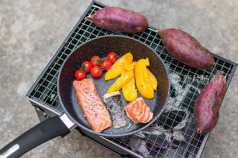 用平底锅煮三文鱼片，用炭炉烤日本红薯。户外烹饪和健康饮食。