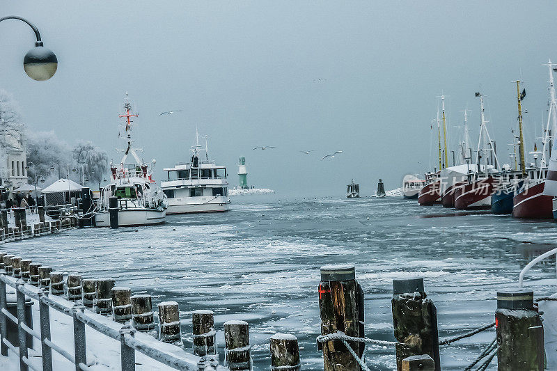 在德国罗斯托克，冰冷的港口与冰冻的大海和船只被困在寒冷的风暴后的大海